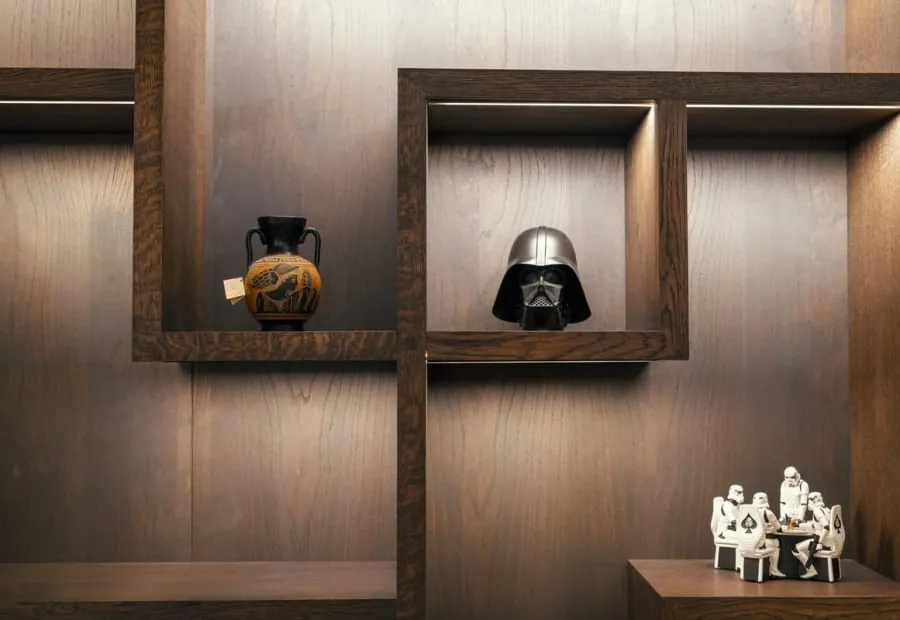 Dark timber panelled wall with lit, offset square display niches holding ornaments, an alcove idea for homes in Torre