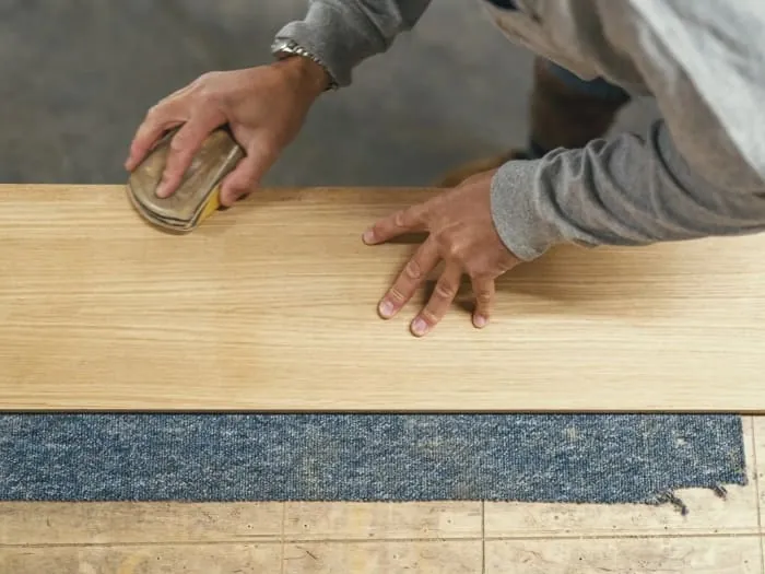 Hand finishing a timber panel in the workshop before delivery