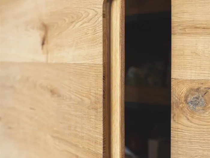 Close-up of a solid oak cupboard door with a finger pull shaped into its edge, joinery of the kind we make for homes in Chelston