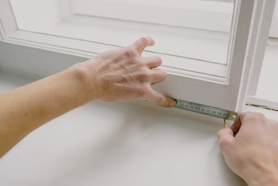 Hands measuring a painted timber window sill with a steel rule, the templating stage of a Torquay bay window seat