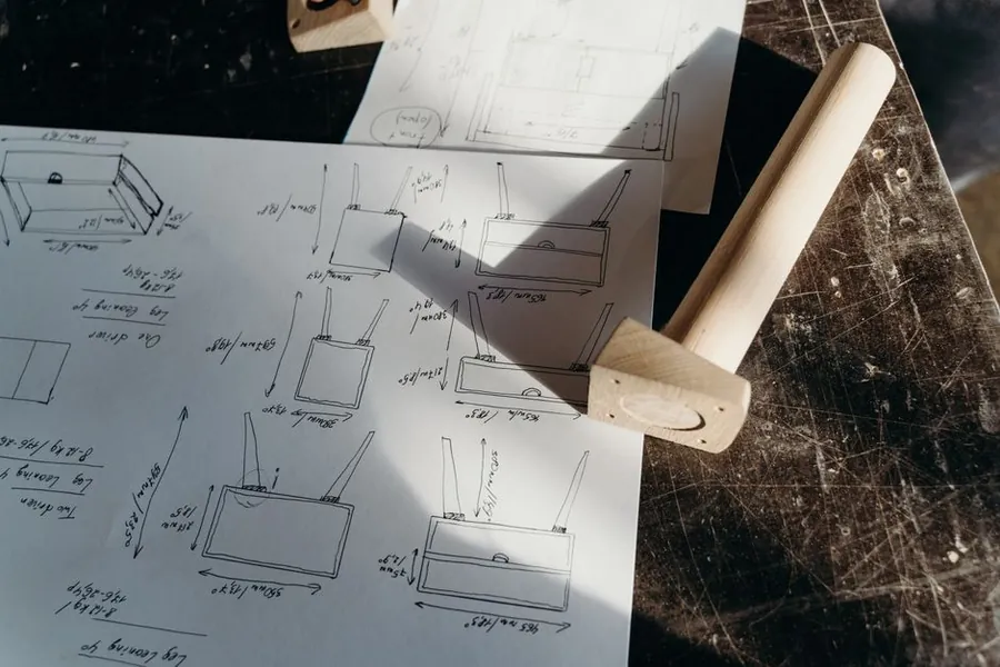Hand-drawn joinery sketches and a wooden mallet on a workbench, the drawings that should come with a written bespoke joinery quote