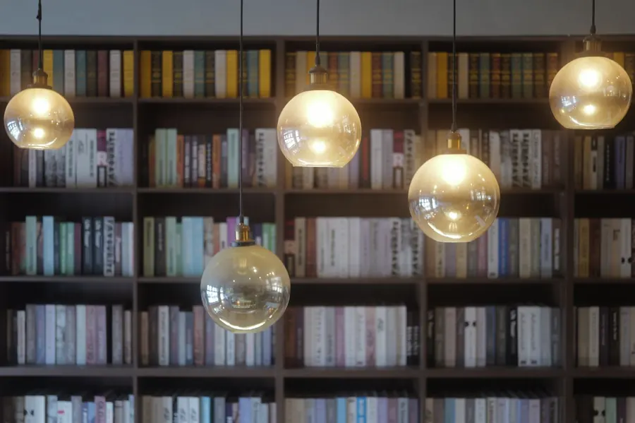 Pendant lights in front of a wall of bookshelves, showing how lighting and shelving need to be planned together