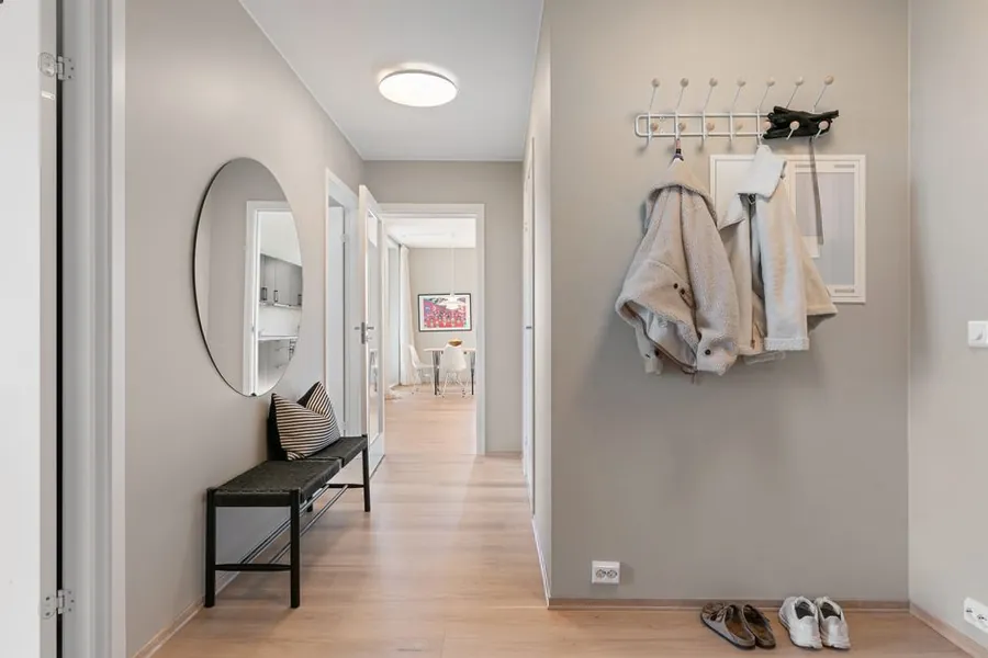 Hallway with a bench, wall hooks and coats by the entrance door, the layout a fitted boot room in Torquay is built around