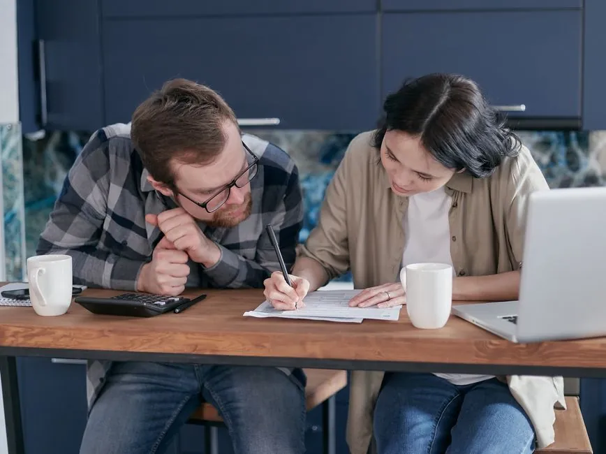 Couple going through a written quote and paperwork together at a kitchen table before paying a deposit for bespoke joinery