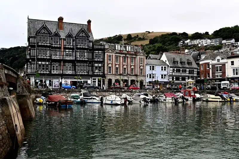 Small boats moored in Dartmouth's inner harbour, with timber-fronted and painted historic buildings along the quay