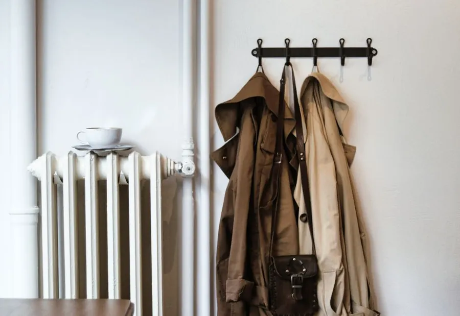 Wet coats hanging on a hook rail beside a radiator in a hallway, the drying problem a Torquay boot room has to solve