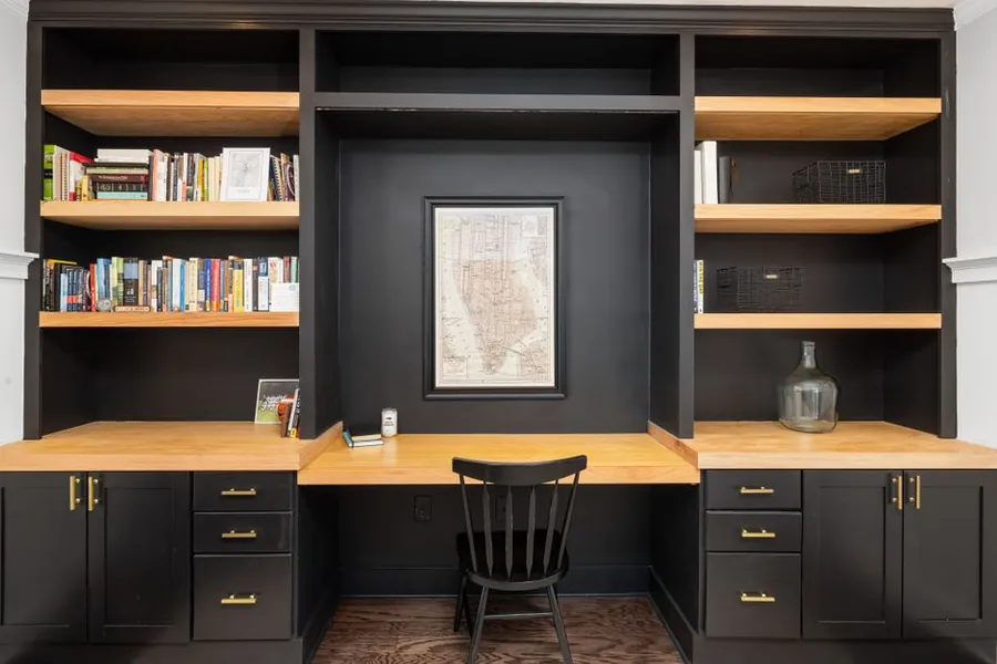 Fitted desk and shelving unit built into a room, showing how a workshop-made home office scribes around the actual wall