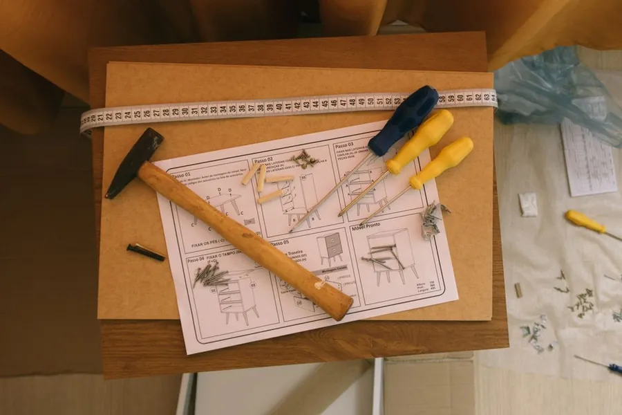 Flat-pack furniture assembly instructions with screwdrivers and a hammer, a reminder that assembling bought units is not bespoke joinery