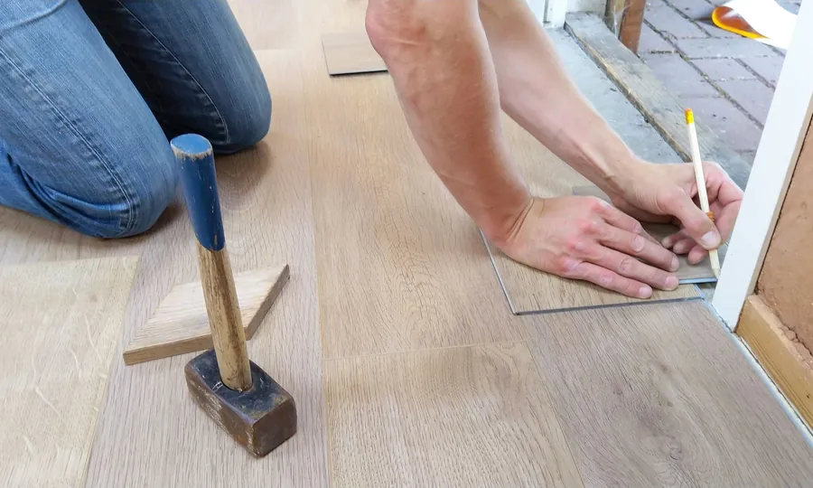 Marking a floor board at a threshold while recording floor levels for a joinery survey in Torquay