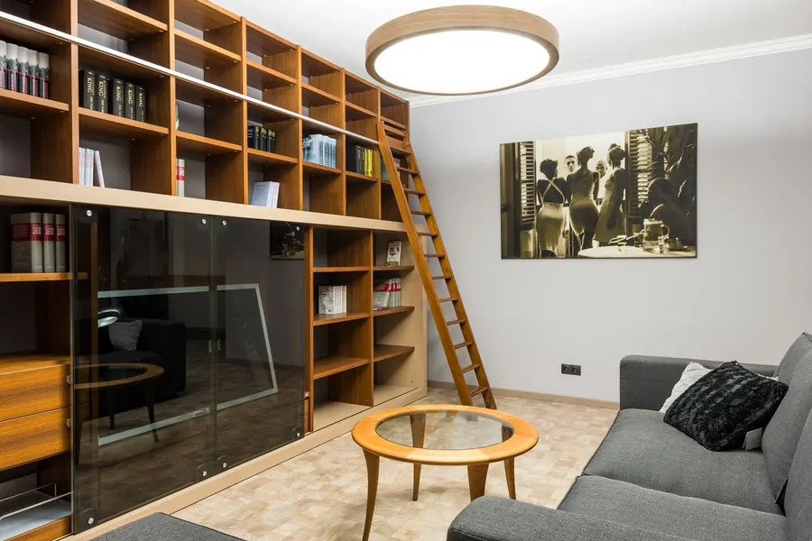 Full-height library wall of timber shelving with a sliding ladder, the kind of floor-to-ceiling bookcase suited to a tall Torquay villa room