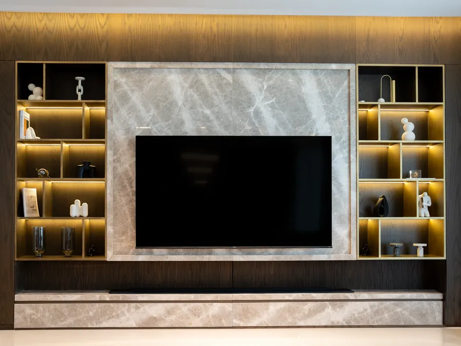 Full-width media wall with lit open shelving either side of a stone-effect television surround, one design option for a Torquay living room