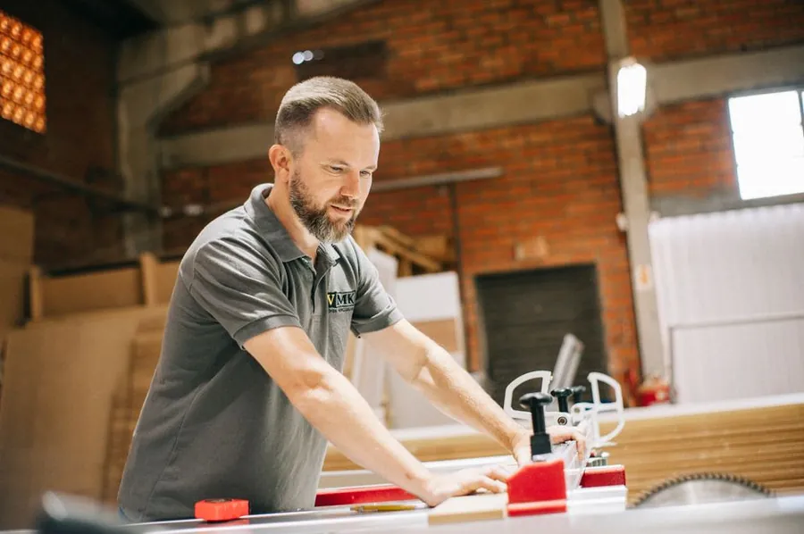 Cabinet maker cutting panels in a workshop, the stage where most of a bespoke kitchen's cost is created