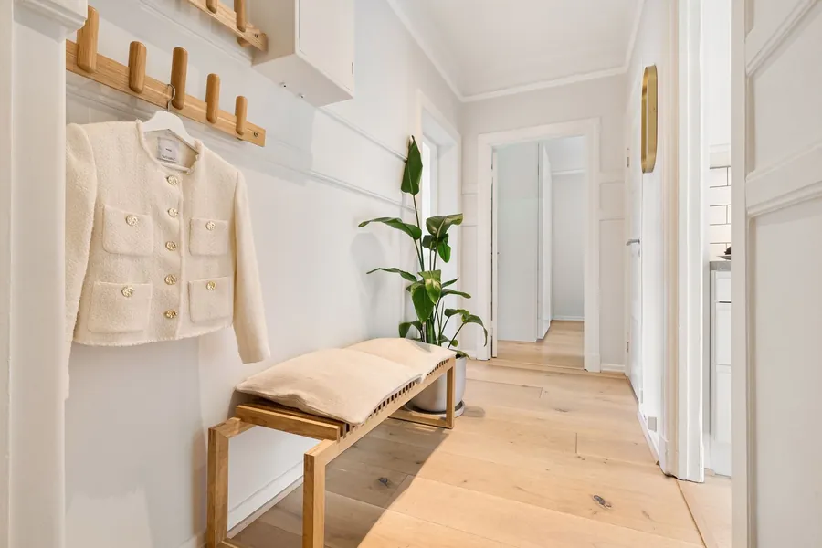 Bright hallway with an oak bench, a peg rail with a hanging jacket and pale timber flooring
