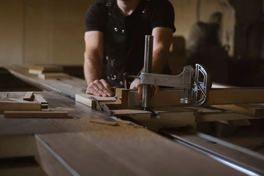 Joiner clamping a timber end panel on a saw bench, the made-to-measure part of a mixed modular and bespoke joinery job in Torquay