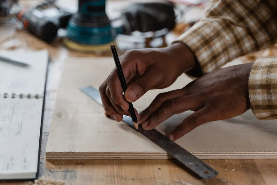 Joiner marking timber against a steel square on the bench, the kind of setting out we do for shutter panels that fit out-of-square Torquay window reveals