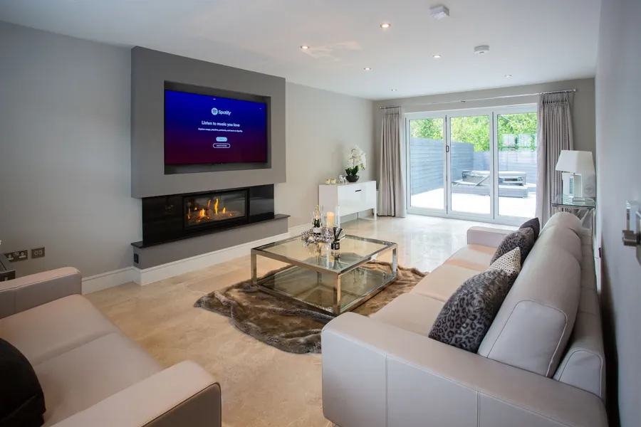 Grey media wall with a recessed screen above a wide fire, with UK sockets on the side wall, the style most Torquay homeowners ask for