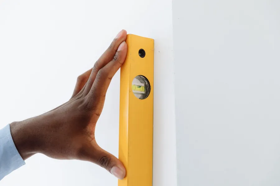 Checking a wall for plumb with a spirit level during a bespoke joinery survey in a Torquay period property