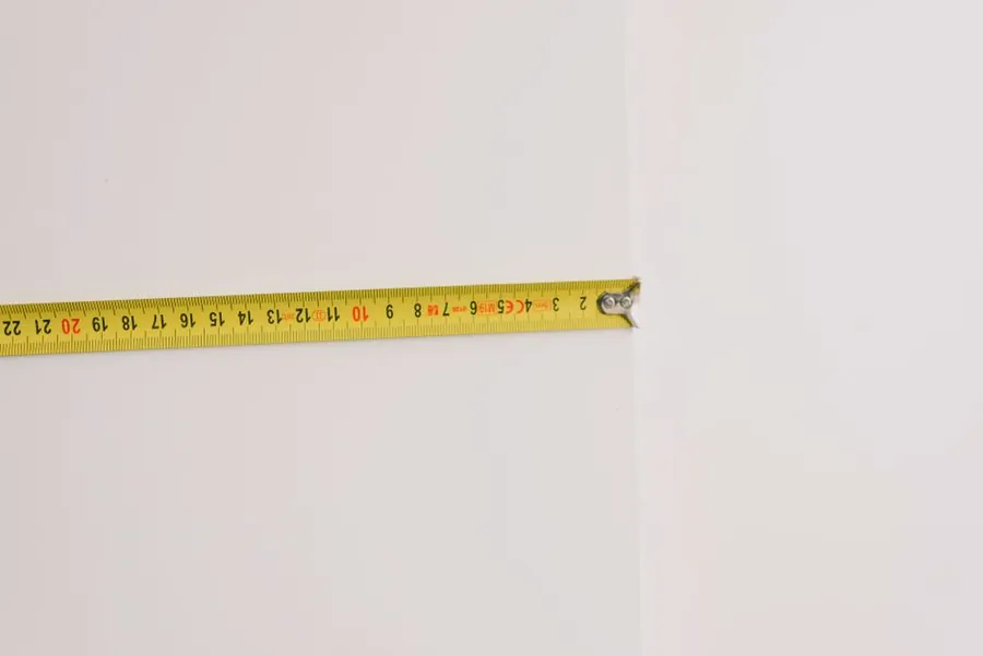 Tape measure held across a wall recess, the check that shows whether a Torquay room suits off-the-shelf or bespoke joinery