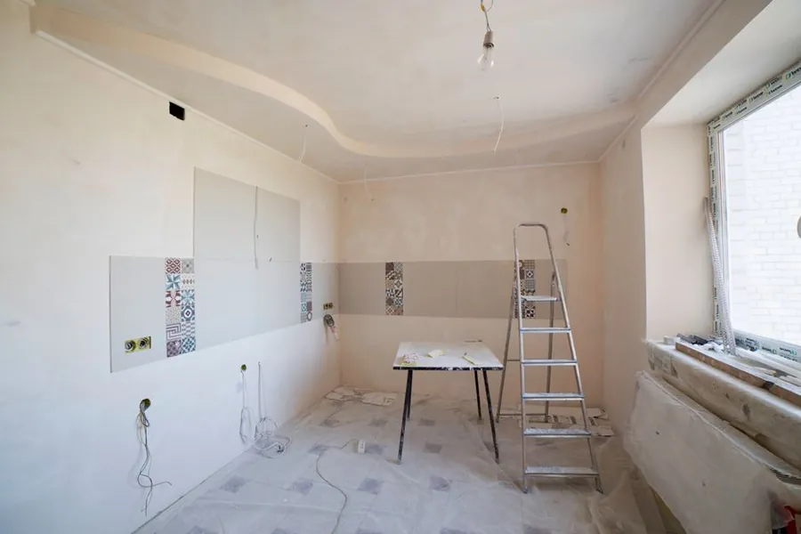 Kitchen mid-renovation with tools and materials, a room being refitted in phases