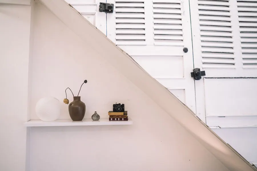 White under-stairs cupboard doors cut to follow the line of the staircase, the kind of raked built-in storage we make for Torquay hallways