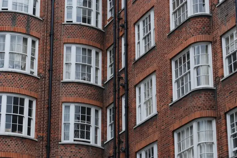 Rows of white-painted timber sash and bay windows on a red brick building, the standard of joinery expected when replacing windows in a Torquay conservation area