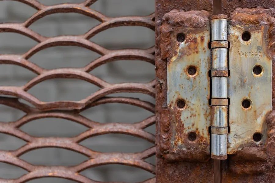 Rusted iron hinge and corroded metalwork of the kind that fails on coastal gates around Torbay