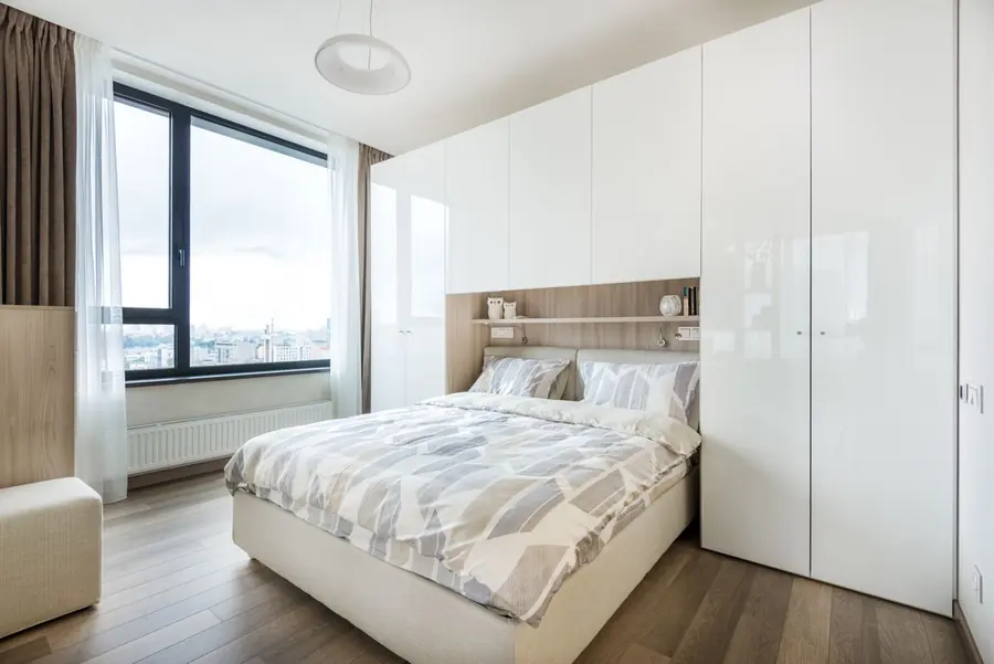 Wall of white built-in wardrobes around a bed, the kind of scheme both national brands and joiners will quote for