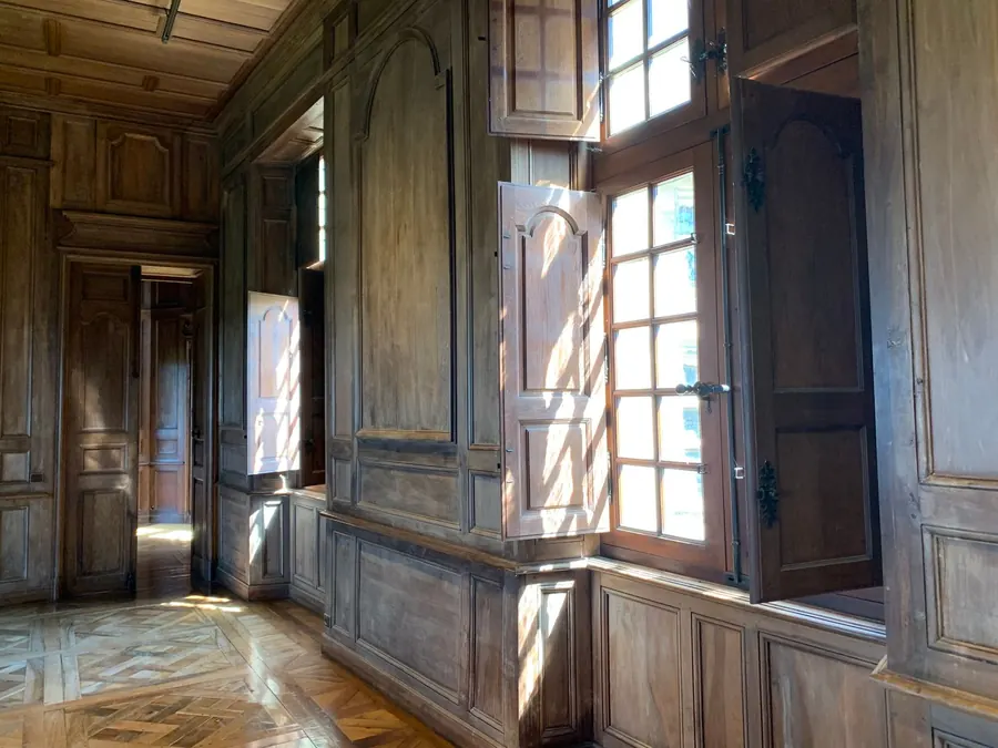 Solid fielded timber shutters folding back into panelled window linings in a period room, the traditional style still found in some Torquay villas