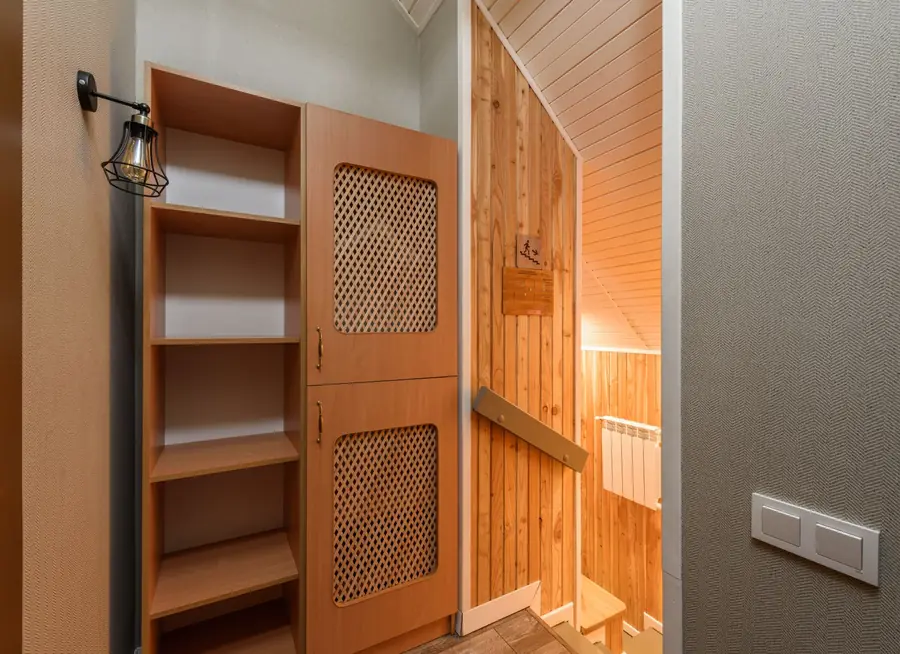 Fitted cupboard with open shelving and a panelled door built into the space beside a narrow staircase