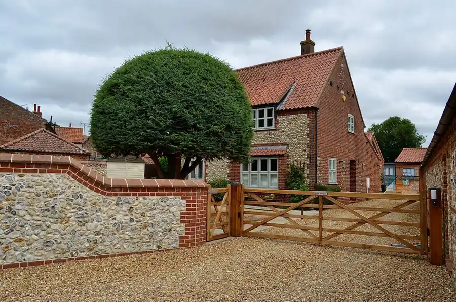 Timber driveway gate at the entrance to a brick and stone cottage, the kind of external joinery made for Torbay homes