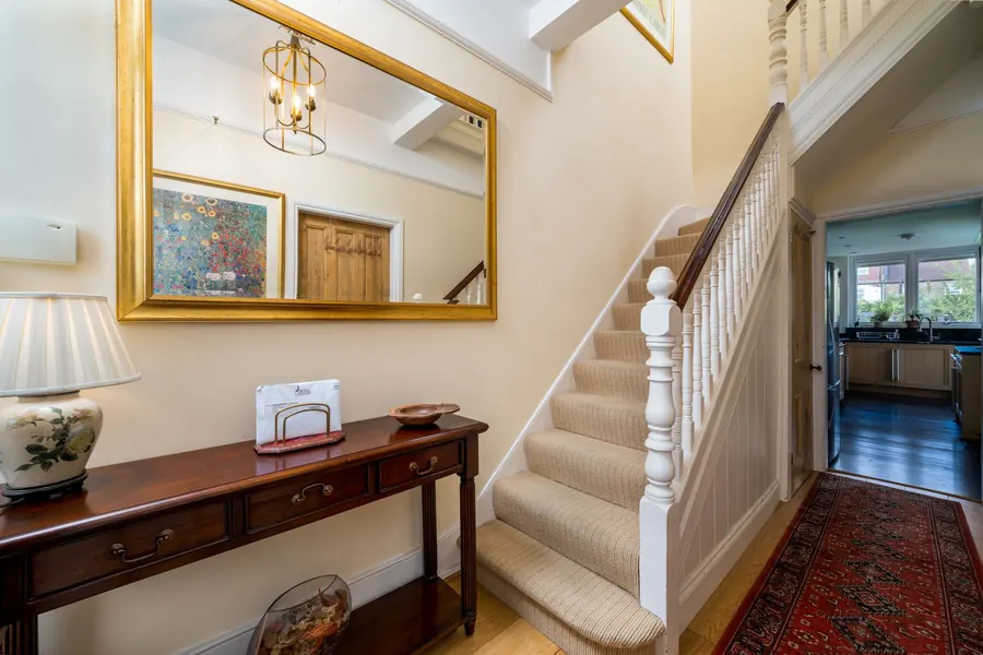 Carpeted staircase rising from a traditional hallway with a console table, the kind of period Torquay hall where the space beneath the flight holds meters and services