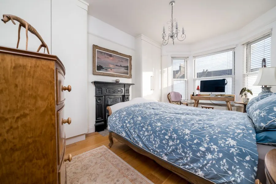 Victorian bedroom with cast iron fireplace, bay window and fitted wardrobes built into the alcoves