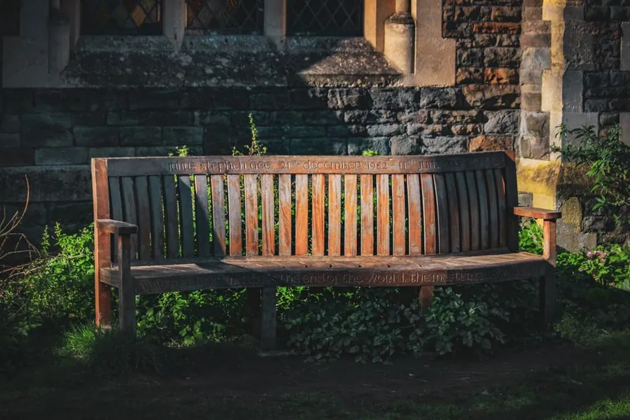 Weathered hardwood bench against a stone wall, showing how outdoor timber silvers in a Torbay garden