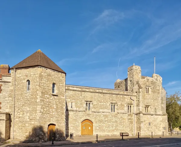 A medieval stone tower and gatehouse building under a clear blue sky