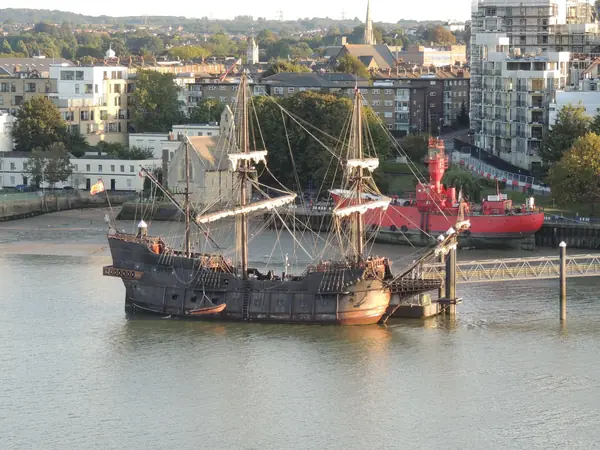 A replica Tudor galleon with tall masts moored at a quayside
