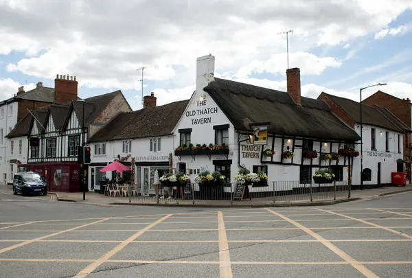 A thatched village pub on a street corner with outside tables