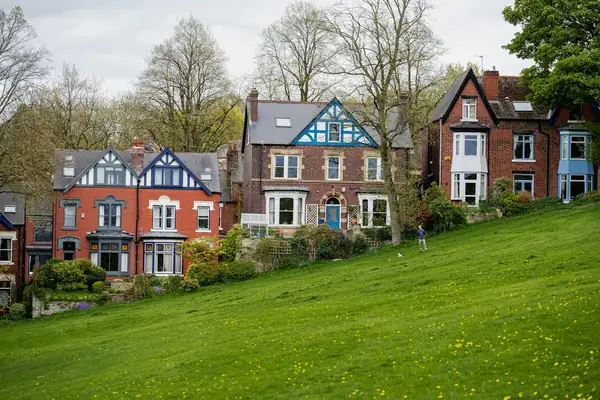 Victorian houses with gables and bay windows facing a green lawn and trees