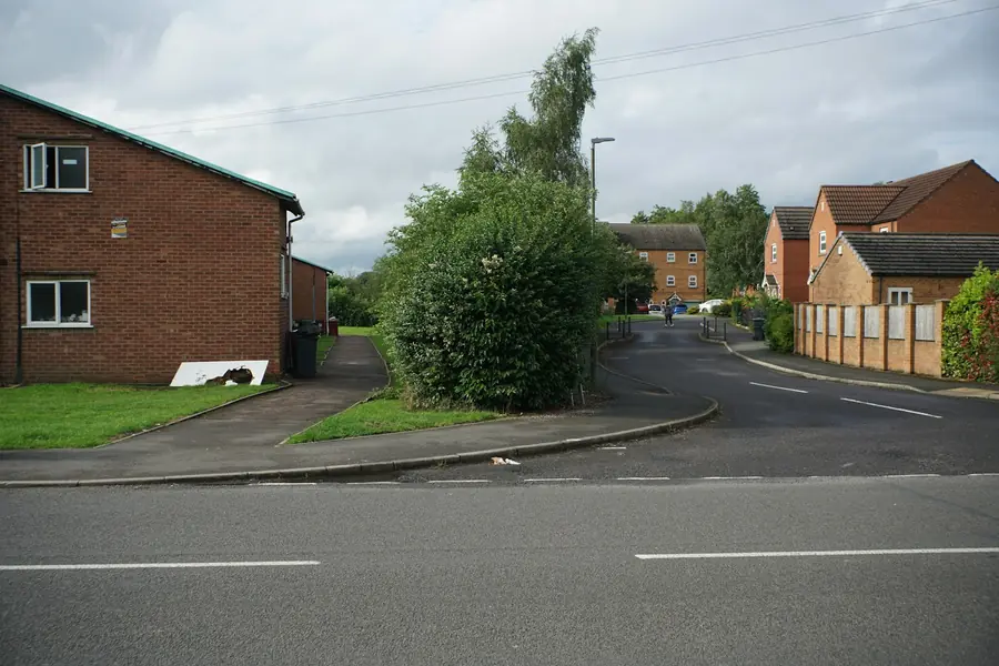 A quiet residential close of brick houses with hedges and young trees