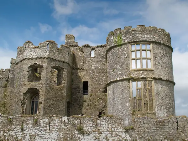 A ruined stone castle with a round tower and empty window openings