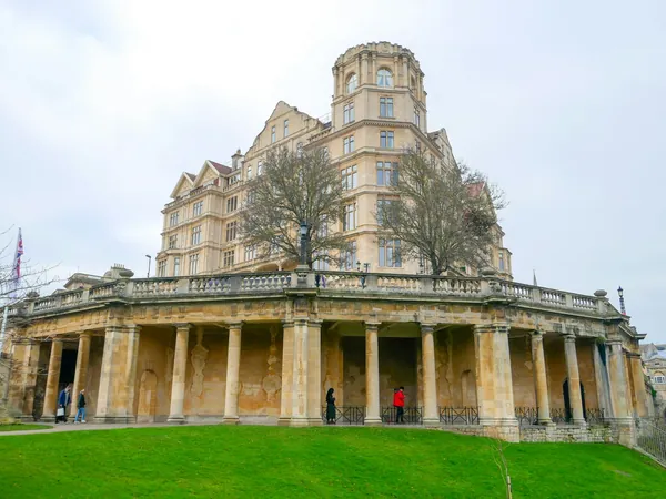 A colonnaded stone mansion front above a lawn