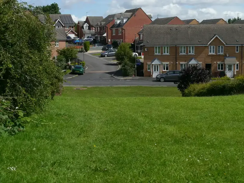 Brick semi-detached houses around a sloping grassy green