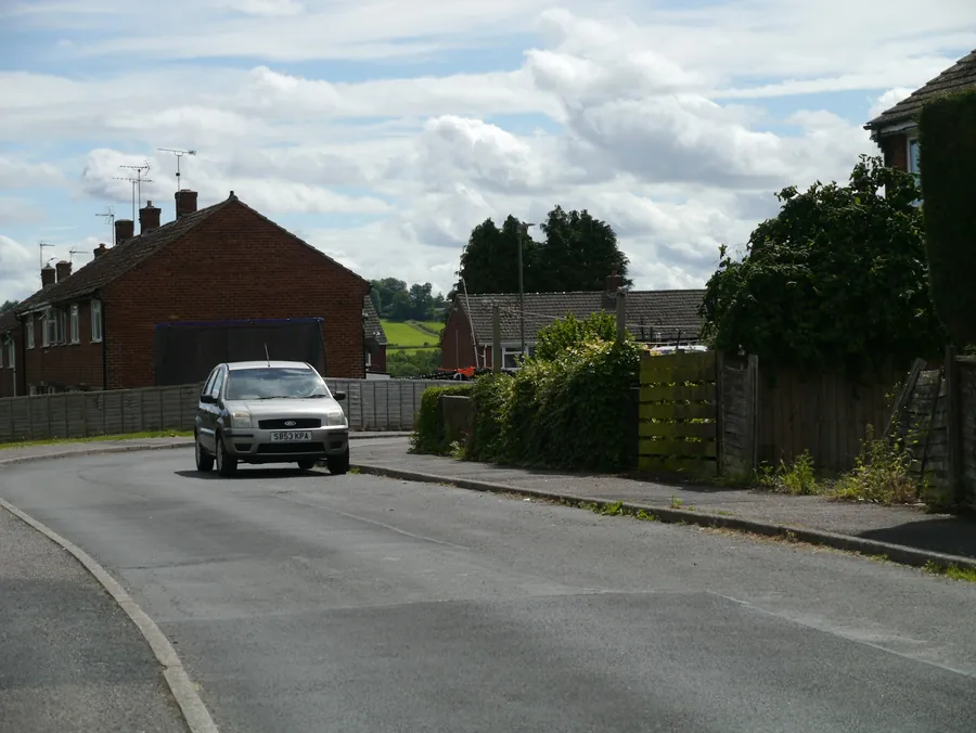 A street of brick semi-detached houses with a car on the road