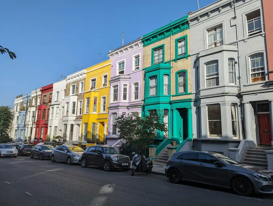 Brightly painted terraced houses with bay windows on a sloping street