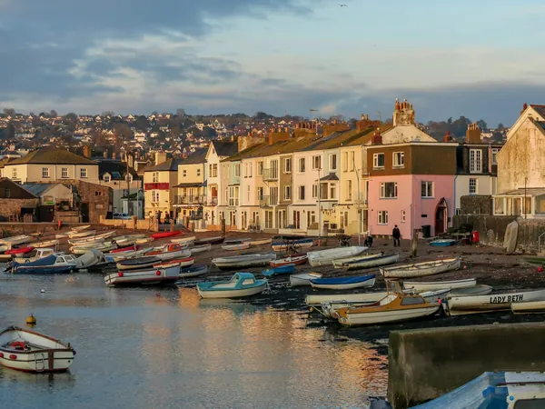 Small boats moored in front of painted waterfront houses in low evening light